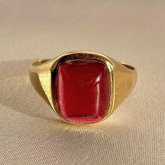 Antique 18k yellow gold ring from the United Kingdom. This signet ring features a vibrant synthetic ruby cabochon. Great antique condition Size: 7.5 resizable* Weight: 3.5 grams Band: 11.1 mm (front), 1.7 mm (back) Synth Ruby: 8.3 mm x 10.0 mm Hallmarks:18CT Luxury Red Cabochon Ruby Ring, Formal Fine Jewelry Signet Ring With Cabochon, Formal Cabochon Signet Ring, Classic Yellow Gold Signet Ring With Cabochon, Classic 14k Gold Signet Ring With Cabochon, Modern Yellow Gold Signet Ring With Cabochon, Modern Gold Signet Ring With Cabochon, 14k Gold Domed Signet Ring With Gemstone, Classic Domed Cabochon Signet Ring