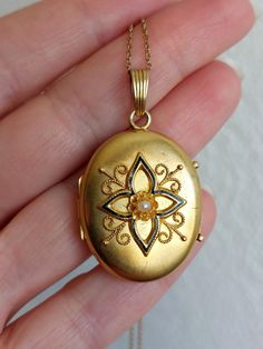 Beautiful gold locket with a four point star pattern, enhanced with black enamel, cannetille details, and a seed pearl at the center. The pearl setting has a eight petals flower shape, onto which prongs are added.  The locket has a matte gold finish, with beautiful patina to it. The back is plain. On the last picture the locket is shown worn on an antique watch chain which is also available in the shop. Details: The locket dates from the Victorian era, 1850-1900. It is not stamped and I believe Victorian Enamel Locket Jewelry, Antique Gold Jewelry For Opera, Oval Enamel Locket Jewelry, Victorian Oval Jewelry For Opera, Victorian Hallmarked Jewelry For Opera, Elegant Enamel Flower Shaped Jewelry, Elegant Oval Enamel Jewelry, Antique Enamel Locket Jewelry, Antique Pendant Jewelry For Opera