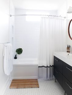 a white bathroom with black and white accessories on the vanity, shower curtain, and bathtub