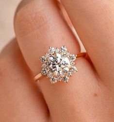 a woman's hand with an engagement ring on it, and the center stone is surrounded by small diamonds