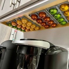 a coffee maker sitting on top of a counter next to a shelf filled with cupcakes