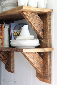 the shelves are made out of wood and have white dishes on them