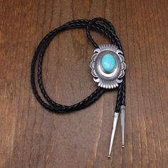 Beautiful sterling silver and turquoise bolo tie. The concho style oval is 2 1/2" tall x 1 3/4" wide. The turquoise is 24 mm tall. The cord and tips are 43" long. The back is stamped Sterling. There is no signature. The work is Navajo style. The domed center is accented with the turquoise stone and stamp work. The edge has cut work and stamp work. It is in good condition. Thank you for shopping in our store. Please let us know if you have questions. BOLO-1576K k *The color you see on your screen Turquoise Bolo Tie, Navajo Style, Bolo Ties, Bolo Tie, Work It, Tie Accessories, Cut Work, Suit And Tie, Turquoise Stone