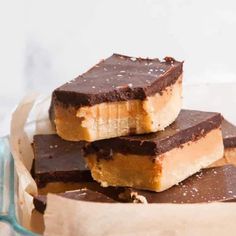 three pieces of chocolate peanut butter bars stacked on top of each other in a glass bowl