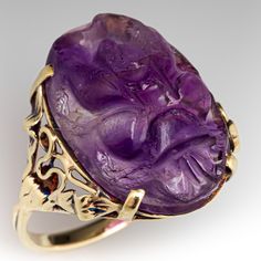 This vintage ring is centered with a four-prong set carved amethyst oval cabochon weighing 10.45 carats. The shoulders are accented with an open vine and leaf design. The ring measures 20.8mm at the top, rises 6.6mm above the finger, tapering to 1.9mm wide and 1.1mm thick at the base of the shank.  The ring is crafted in 14k yellow gold and is currently a size 8.75. Luxury Amethyst Cabochon Ring For Formal Occasions, Luxury Formal Cabochon Amethyst Ring, Luxury Formal Amethyst Cabochon Ring, Luxury Purple Cabochon Amethyst Ring, Luxury Purple Amethyst Cabochon Ring, Formal Cabochon Amethyst Ring Fine Jewelry, Luxury Amethyst Cabochon Ring, Formal Amethyst Oval Cabochon Jewelry, Formal Amethyst Jewelry, Oval Cabochon