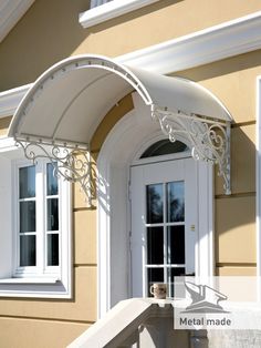 a white awning on the side of a house next to a door and windows