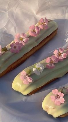 two cookies decorated with pink flowers and white icing on top of a table cloth