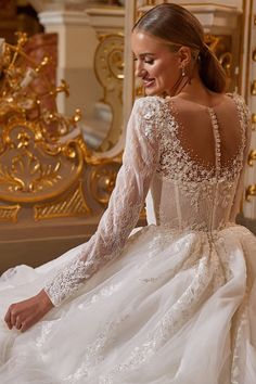 a woman in a white wedding dress sitting on the floor with her back to the camera