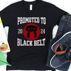 Celebrate a milestone in your young martial artist's journey with this personalized "Promoted to Black Belt" t-shirt! 🥋 This custom tee is not only a symbol of hard-earned success but also a keepsake that commemorates their dedication and the year they achieved this impressive rank. Crafted from comfortable materials that stand up to rigorous training sessions or casual wear, this tee is perfect for any occasion. -Personalize with the year of achievement -Durable and comfortable fabric for acti Black Crew Neck T-shirt For School Spirit, Black Team Spirit T-shirt With Letter Print, Black T-shirt With Name Print For Fans, Black T-shirt With Custom Print For Fans, Black Custom Print Fan Apparel T-shirt, Black Custom Print T-shirt, Fan Apparel, Black Custom Print Fan T-shirt, Sporty Black T-shirt With Custom Print, Black School Spirit T-shirt With Name Print