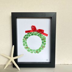 a frame with a christmas wreath and starfish on the side, next to it