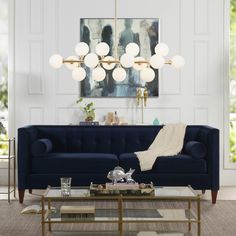 a living room with a blue couch, coffee table and large painting on the wall