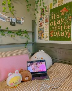 a laptop computer sitting on top of a bed next to a stuffed animal and pillow