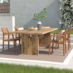 a wooden table with chairs around it on a patio next to a wall and grass