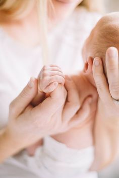 two adults holding a baby's foot in their hands