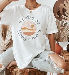 We Rise By Lifting Others Shirt | Positive Quote Shirt | Christian Shirts | Inspirational Shirts | Teacher Appreciation Summer Sunrise Shirt ▹ SIZING AND ITEM DETAILS * T-Shirt sizes are UNISEX. Please check photos for detailed measurements. Try comparing the measurements to your favorite t-shirt that fits just the way you like it! * Main photo shows the White t-shirt. Design can also be printed on Athletic Heather. Clicking on each color in the dropdown box will show that color's photo. * White is 100% combed and ring-spun cotton * Athletic Heather is 90% combed and ring-spun cotton, 10% polyester * Fabric weight: 4.2 oz (142 g/m2) * Pre-shrunk fabric * Side-seamed construction * Design is printed using direct-to-garment (DTG) print on Bella Canvas 3001 t-shirts. All inks used are water-b Comfortable Fit Short Sleeve Summer Tops, Casual White Print Shirt With Relaxed Fit, Spring Shirt With Front Print And Relaxed Fit, Spring Shirt With Front Print In Relaxed Fit, White Tops With Front Print For Spring, White Top With Front Print For Spring, White Comfortable Fit Tops For Everyday, White Everyday Comfortable Tops, White Comfortable Top For Everyday