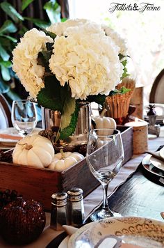 there is a vase with white flowers in it on top of a wooden box at the table