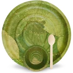 a green paper plate with a white spoon and fork on the side, surrounded by leaves