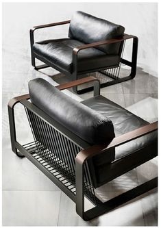 two black leather chairs sitting next to each other on top of a white tile floor