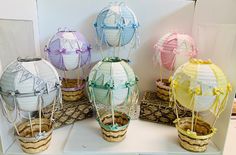 there are many different colored paper lanterns in baskets on the table with ribbons tied around them