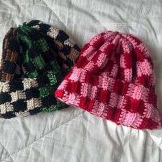 two knitted hats sitting on top of a bed