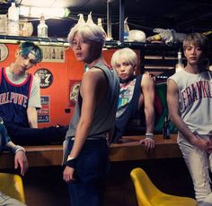 the group of young men are posing for a photo in front of a bar with yellow chairs