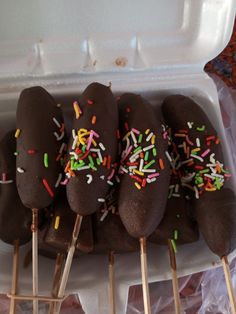 chocolate covered donuts with sprinkles on skewers in an ice box