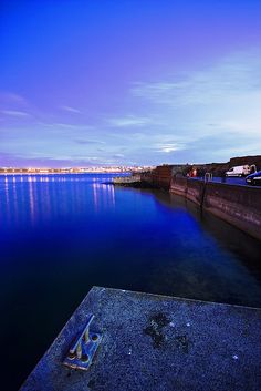 a body of water that has some cars parked on the side of it at night