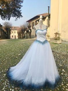 a blue and white wedding dress on display in front of a building with stone flooring