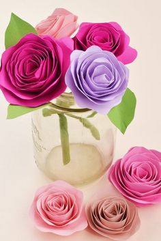 pink and purple paper roses in a vase with three smaller ones sitting next to each other