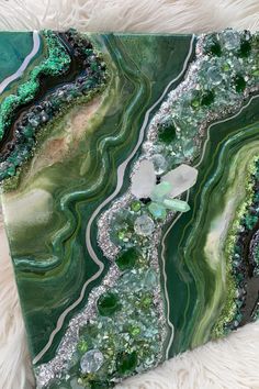 a green and black marble with silver glitters on the edges is sitting on a white furnishing