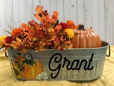 a metal tub filled with flowers and pumpkins