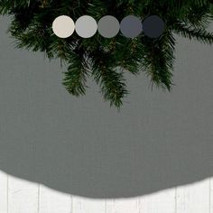 a christmas tree with white and black circles hanging from it's branches in front of a gray background