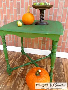 a green table with two pumpkins on it and a small cake stand in the background