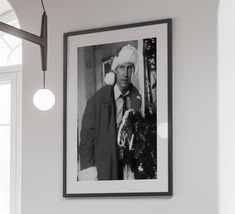 a black and white photo of a man wearing a santa claus hat hanging on the wall