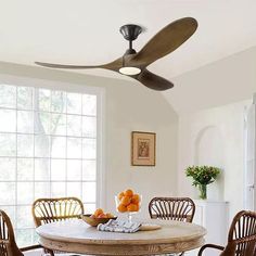 a dining room table with four chairs and a ceiling fan in the middle of it