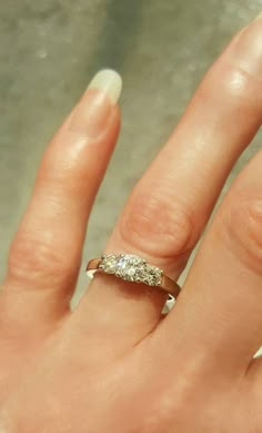 a woman's hand with a diamond ring on top of her left hand,