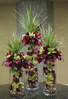 three vases filled with flowers and plants on a table