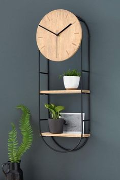 a clock mounted to the side of a wall next to a potted plant on a shelf