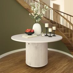 a white table with flowers and candles on it in the middle of a room next to stairs