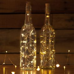 two bottles with fairy lights in them on a table