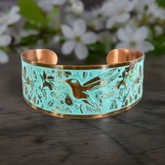 Solid Copper Patina Cuff Bracelet With Hummingbird & Floral Motif, Light Verdigris Rustic Patina Tapered Flat Copper Cuff Bracelet. □ Sizing : 1.25 W x 6.75" L - Adjustable □ Material: Solid Copper □ Motif: Hummingbird/Hibiscus Flowers □ Rustic Light Verdigris Patina This collection of rings & cuffs is available in light or dark verdigris patina as well as flat or concave shapes to choose from. Stunning detail on these beautiful rustic patina copper cuffs. Treated with a rustic teal verdigris patina for that beautiful weathered look. 100% copper, nickel & lead-free. Sealed with triple baked on lacquer which will protect the cuff from oxidation, providing long-lasting wear & durability. To care for your luxury cuff, avoid immersing it in water or exposing it to harsh chemicals. With proper Rustic Light, Patina Copper, Copper Cuff Bracelet, Copper Cuff, Copper Patina, Hibiscus Flowers, Floral Motif, Cuff Bracelet, Hibiscus