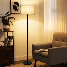 a living room with a chair, lamp and pictures on the wall in it's corner