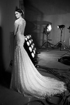 a black and white photo of a woman in a wedding dress with lights behind her