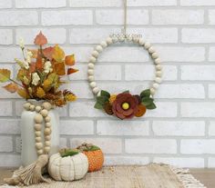 a white vase filled with flowers sitting on top of a table next to a wooden beaded wreath