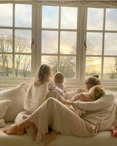 three women sitting on a couch in front of a window