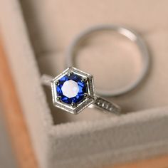 an engagement ring in a box with a blue sapphire stone on the side and diamond accents