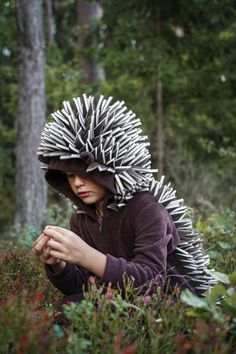 a woman in a hedgehog costume crouches down and looks at her cell phone