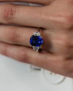 a woman's hand with a ring on it and a blue stone in the middle