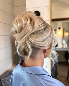 a woman with blonde hair in a bun updo and wearing a blue shirt is looking off to the side