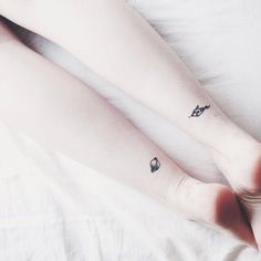 two people with tattoos on their legs laying in bed next to each other and one has a small tattoo on the lower leg